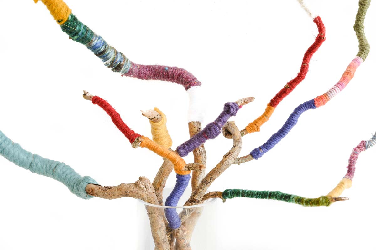 Make a wrapped twig bouquet for an easy and colorful centerpiece! Perfect for yarn odds and ends create this fun upcycled craft for your mantlepiece, bringing nature indoors #homedecor #upcycle #upcycedcraft #twigs #mantlepiecedecor